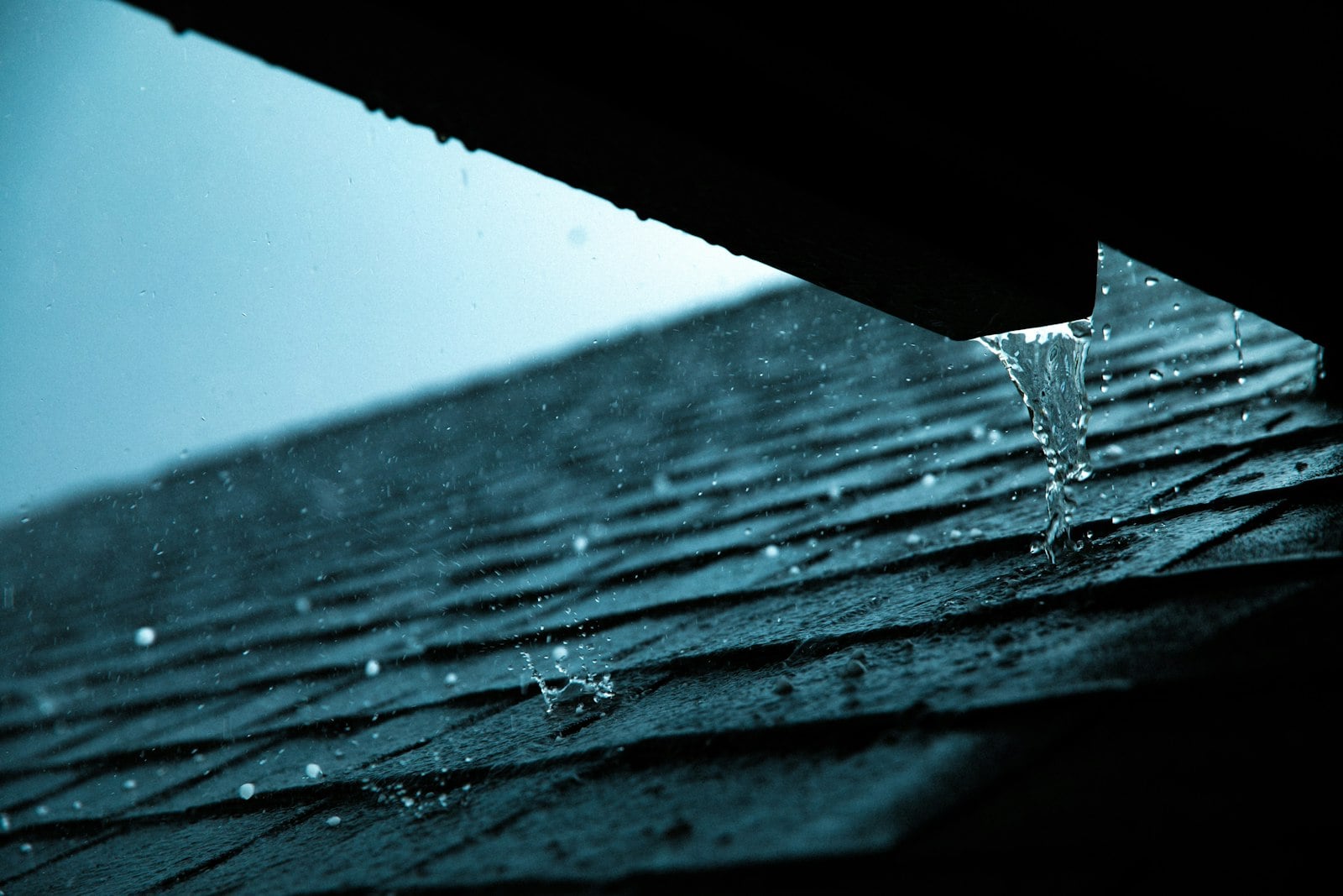 Rain dripping from the edge of a roof gutter