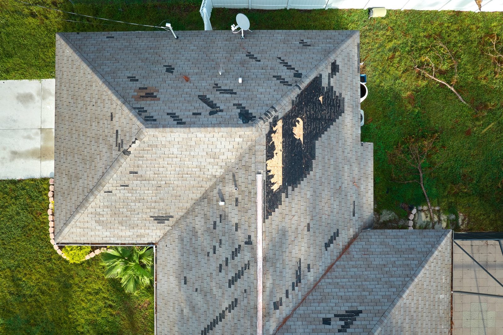 Storm-damaged roof with missing shingles and exposed decking